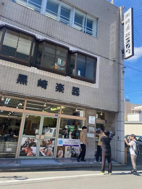 黒崎楽器の店舗前で行われた「デニスのAWAトレジャーハント」の撮影風景