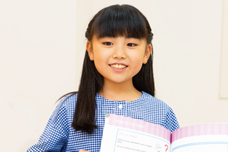 テキストを持って笑顔を見せる小学生