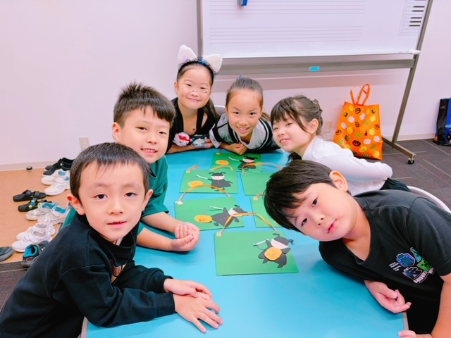ハロウィンの袋を並べたテーブルを囲む子どもたち